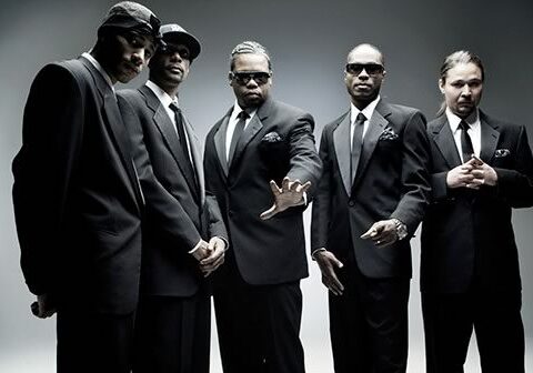 Five men in suits posing together.