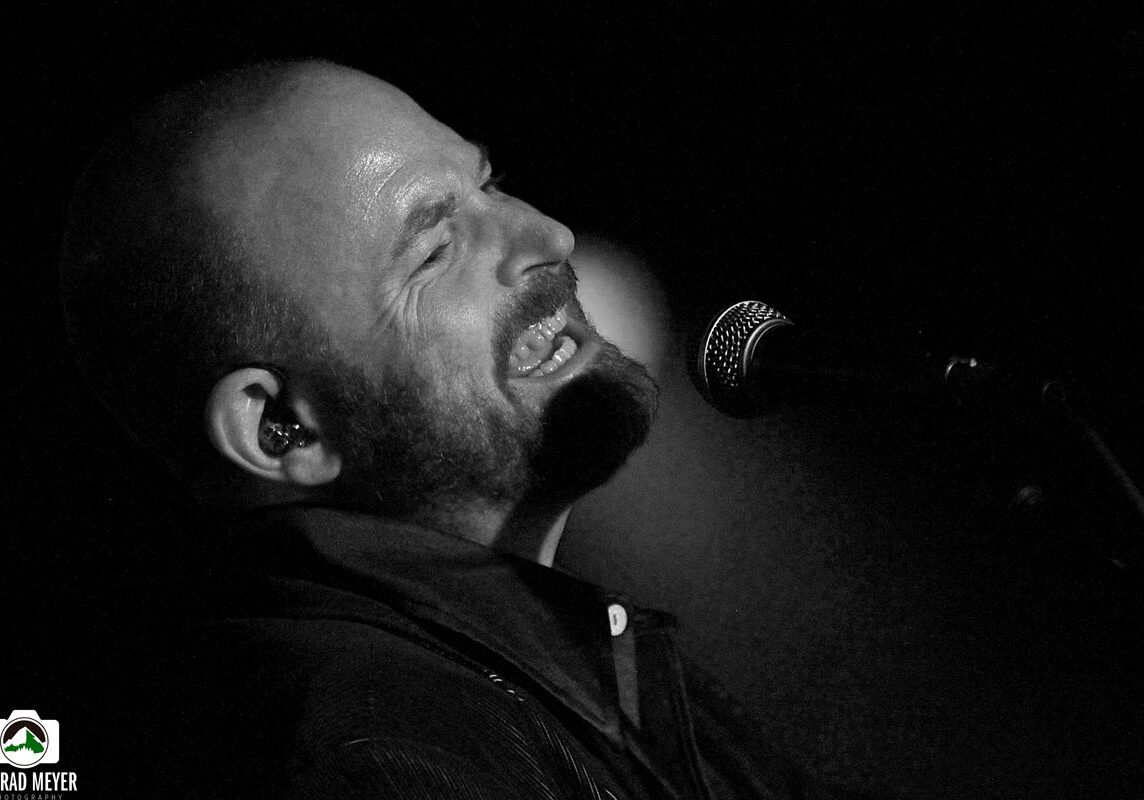 Singer passionately performing on stage, black-and-white.