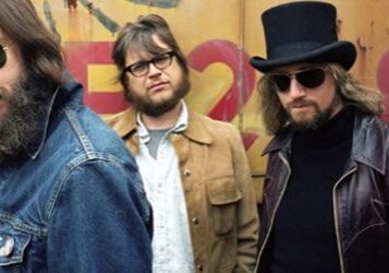 Five men standing in casual clothing outdoors.