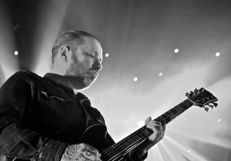 Guitarist performing on stage with spotlight.