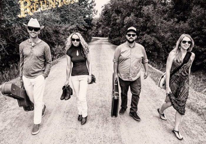 Four people walking on a rural road.