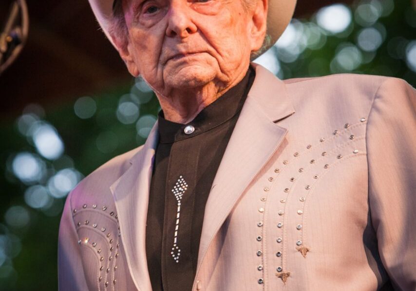 Elderly man in cowboy hat on stage.