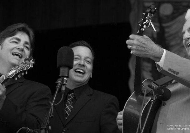 Musicians performing joyfully with guitars on stage.