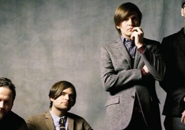 Four men in formal attire, posing together.