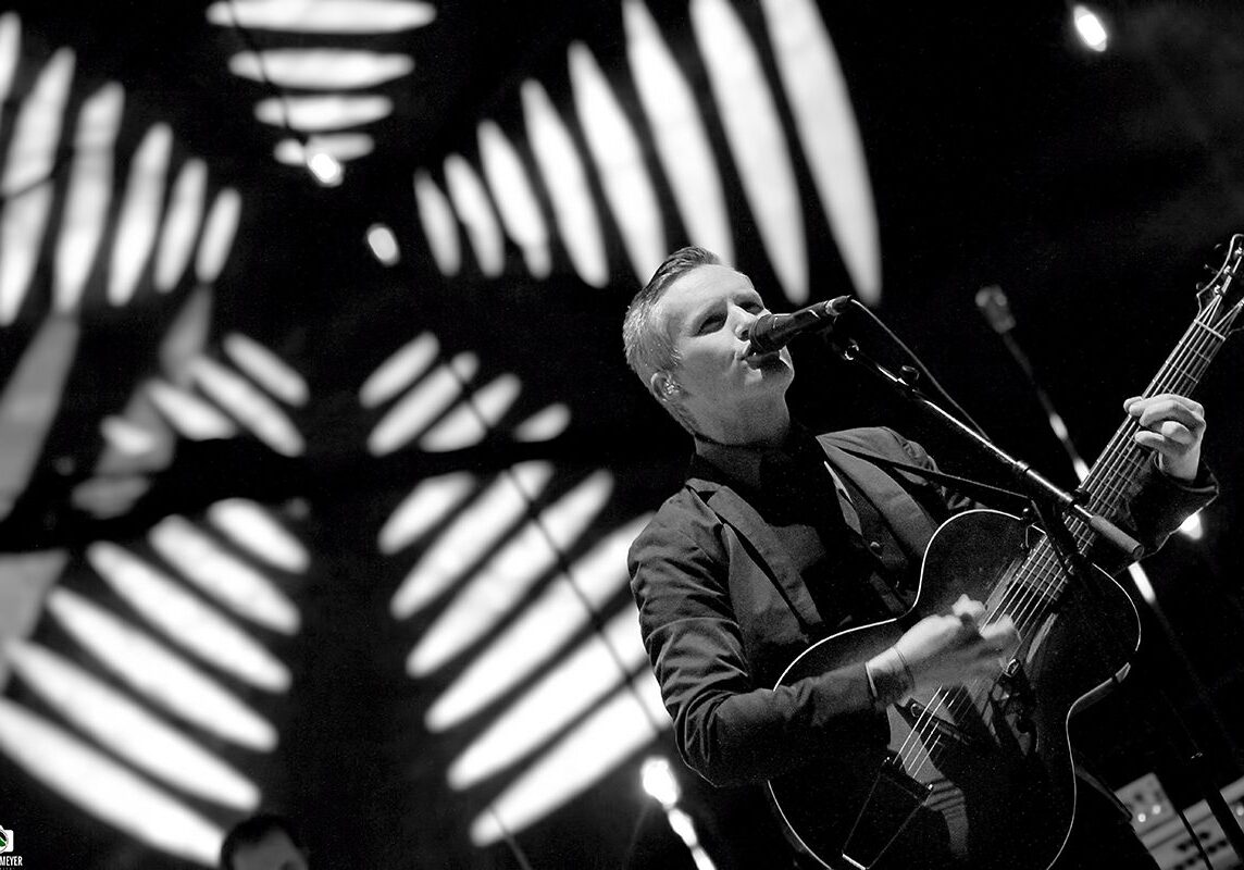 Singer performing on stage with guitar.
