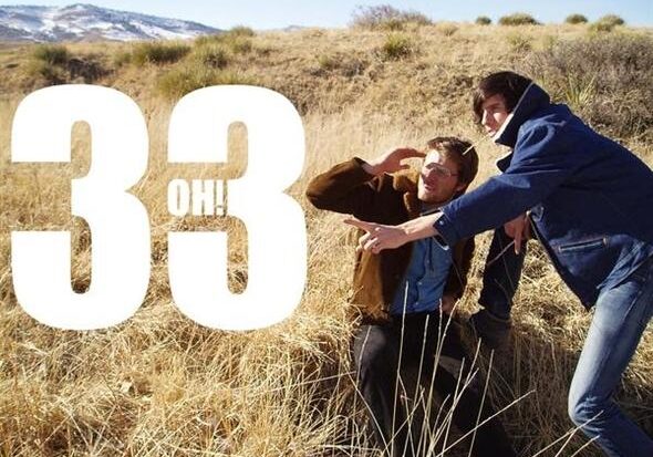 Two people in a grassy field, pointing.