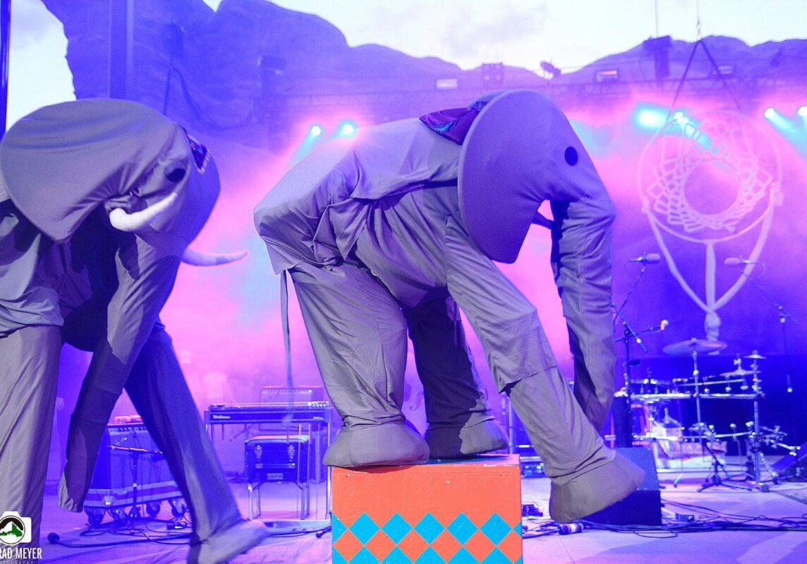 People in elephant costumes performing on stage.