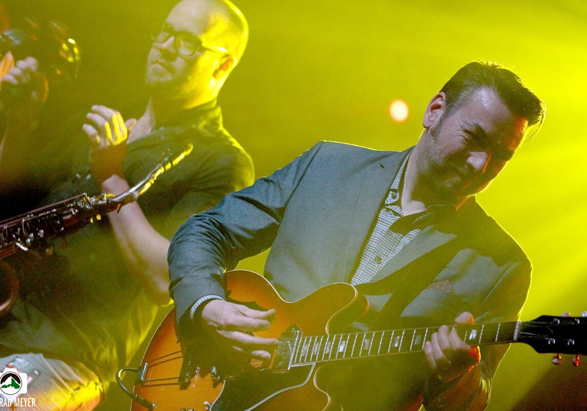 Musicians performing on stage with guitars.