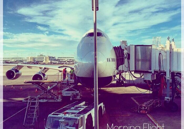 Airplane at airport gate under blue sky.