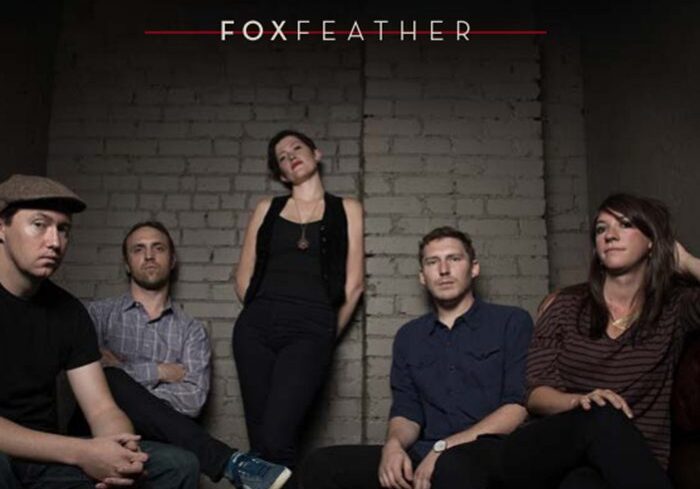 Band members posing against a brick wall.