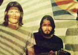 Three men with a guitar and projection.
