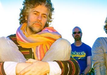 Four men sitting outdoors with colorful scarves.