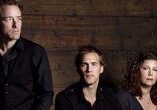 Three people posing against a wooden backdrop.