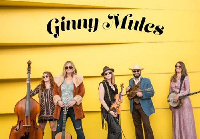 Band posing with instruments against yellow wall.