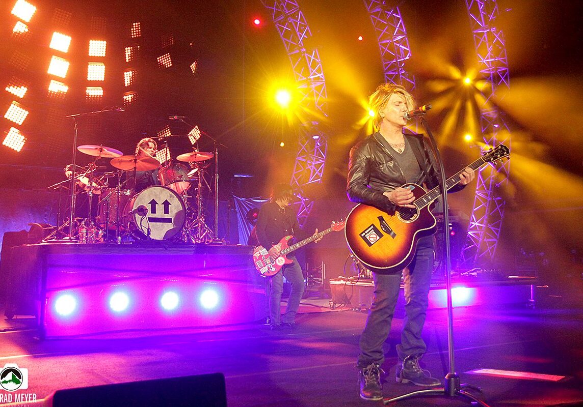 Band performing on stage with colorful lights.