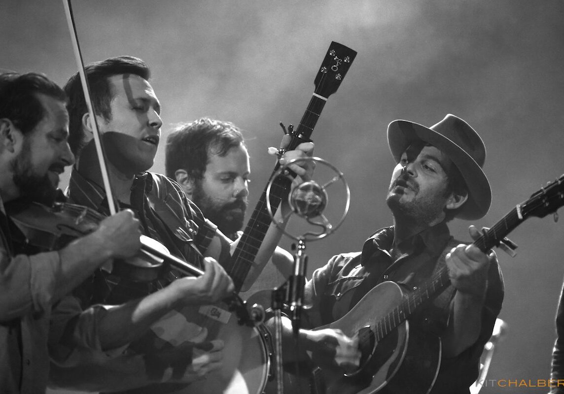 Band performing live with guitars and violin.