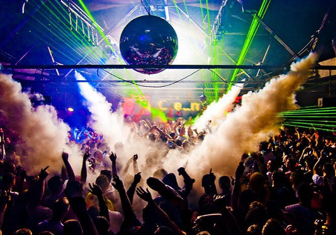 Crowded nightclub with lasers and smoke effects.