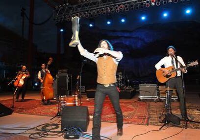 Band performing energetically on stage with instruments.
