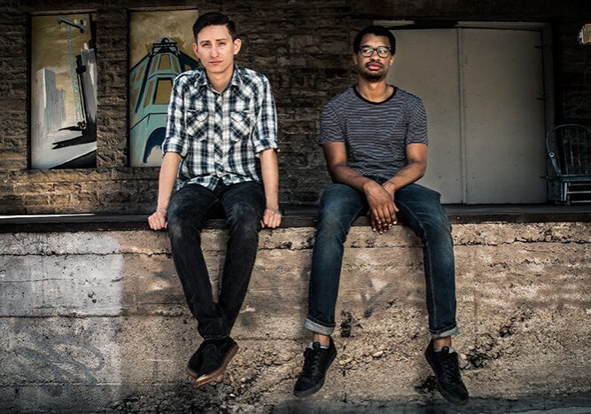 Two men sitting on a concrete ledge.