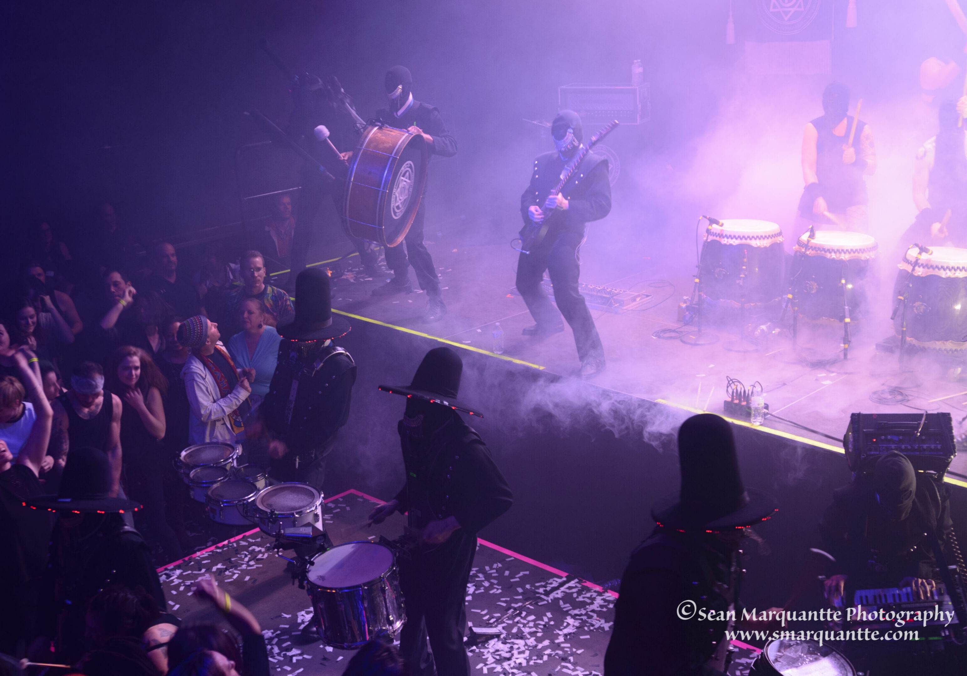 Musicians performing on stage with drums.
