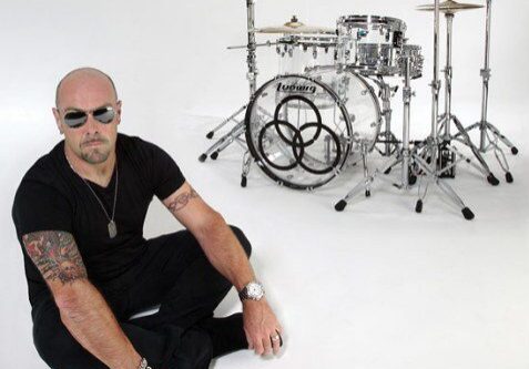 Man sitting near a drum set.