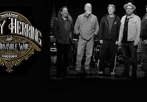 Band standing beside logo on dark background.