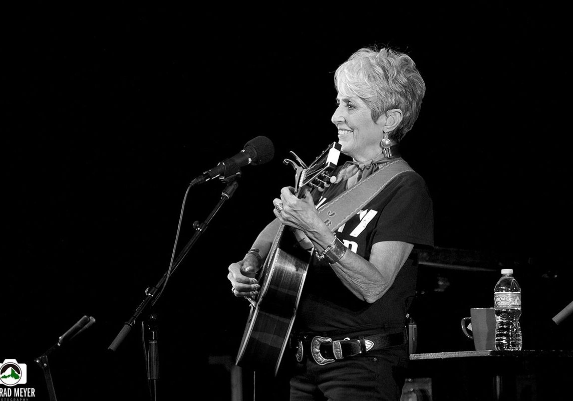 Musician performing with guitar on stage.