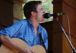 Musician singing and playing guitar on stage.