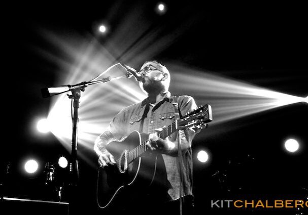 Musician performing on stage with guitar.