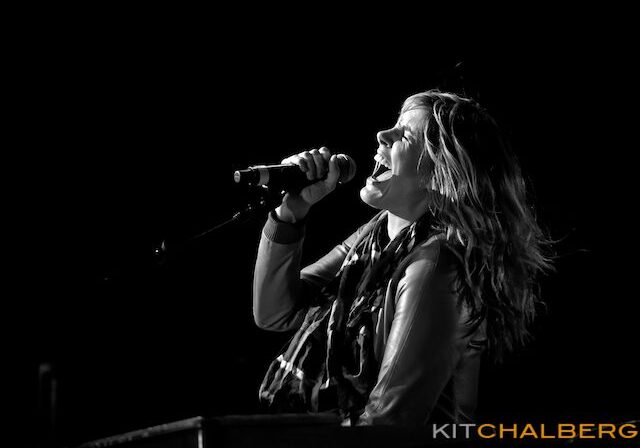 Singer passionately performing on stage, black-and-white.
