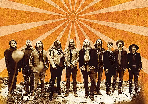 Band standing against an orange sunburst background.