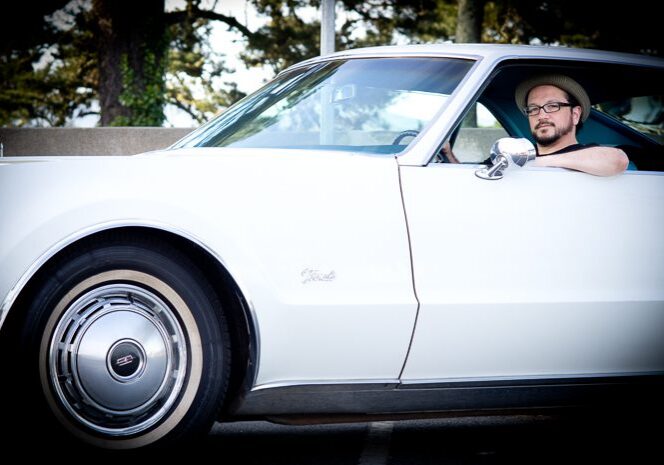 Man driving a vintage white car.
