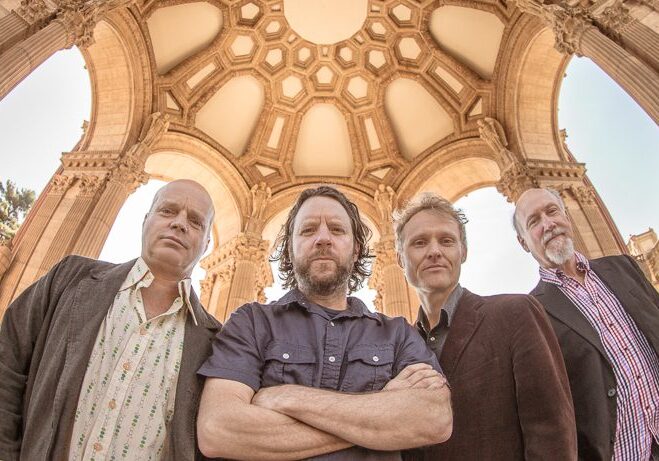 Four men standing under ornate dome.