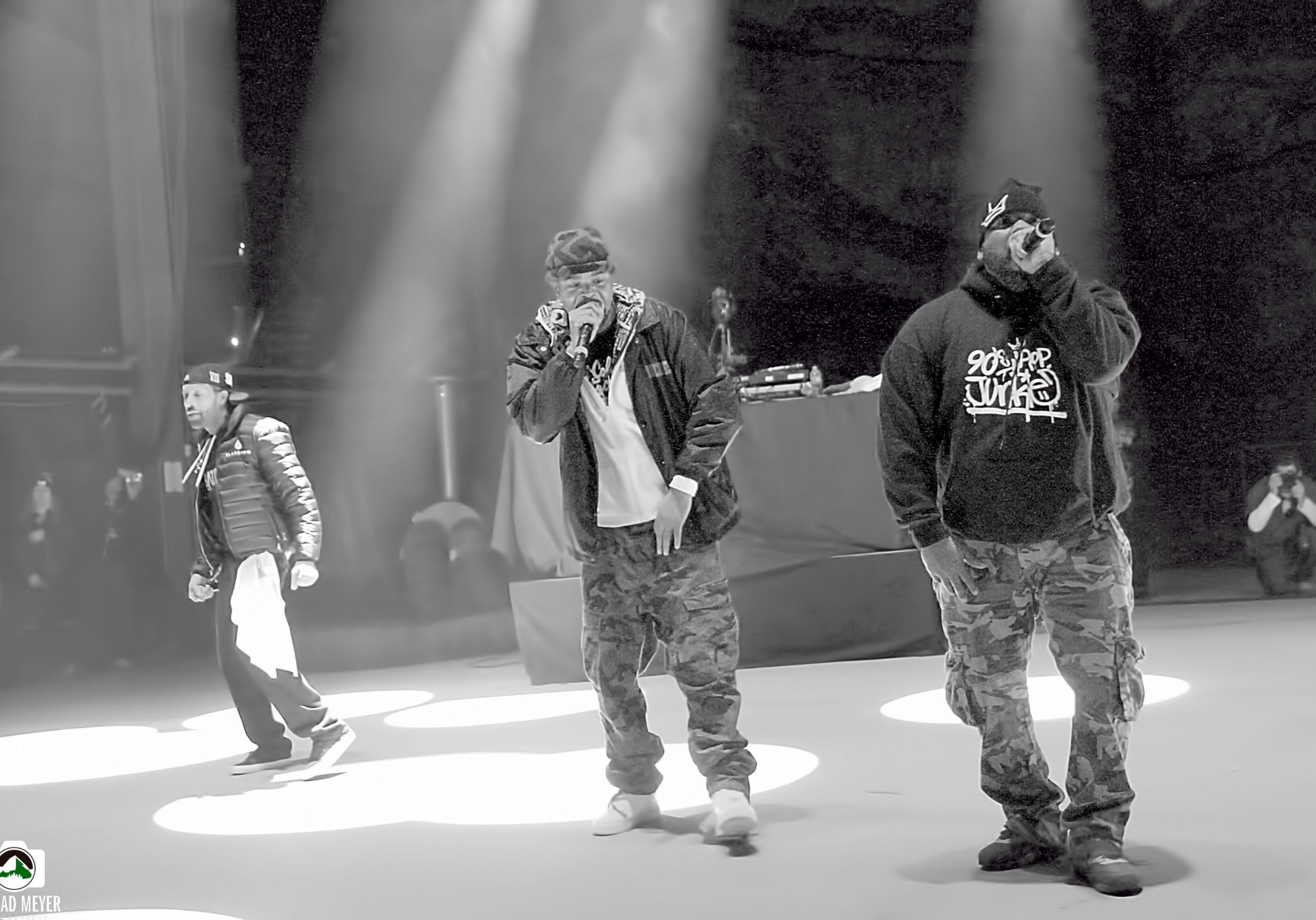 Rap group performing on stage under lights.