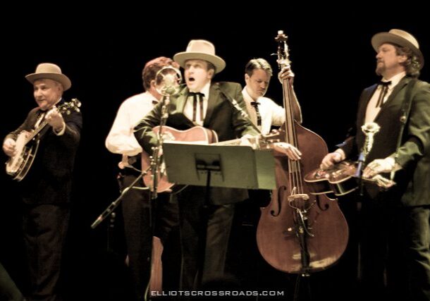 Band performing on stage with various instruments.