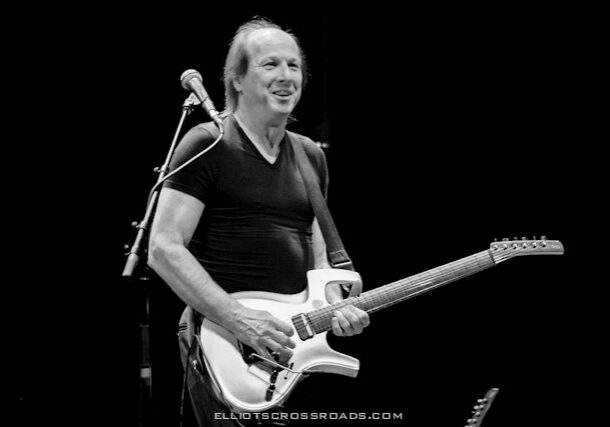 Musician playing electric guitar on stage.