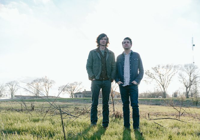 Two men standing in a grassy field.