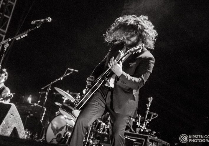 Guitarist performing energetically on stage.