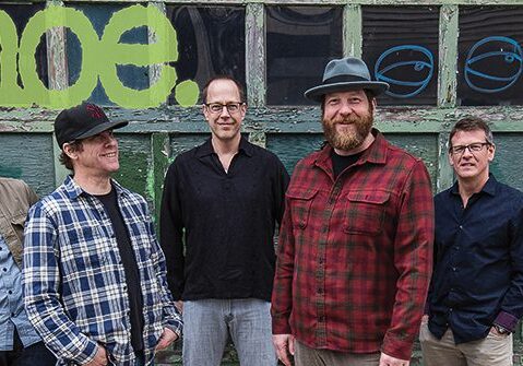 Five men standing in front of graffiti.