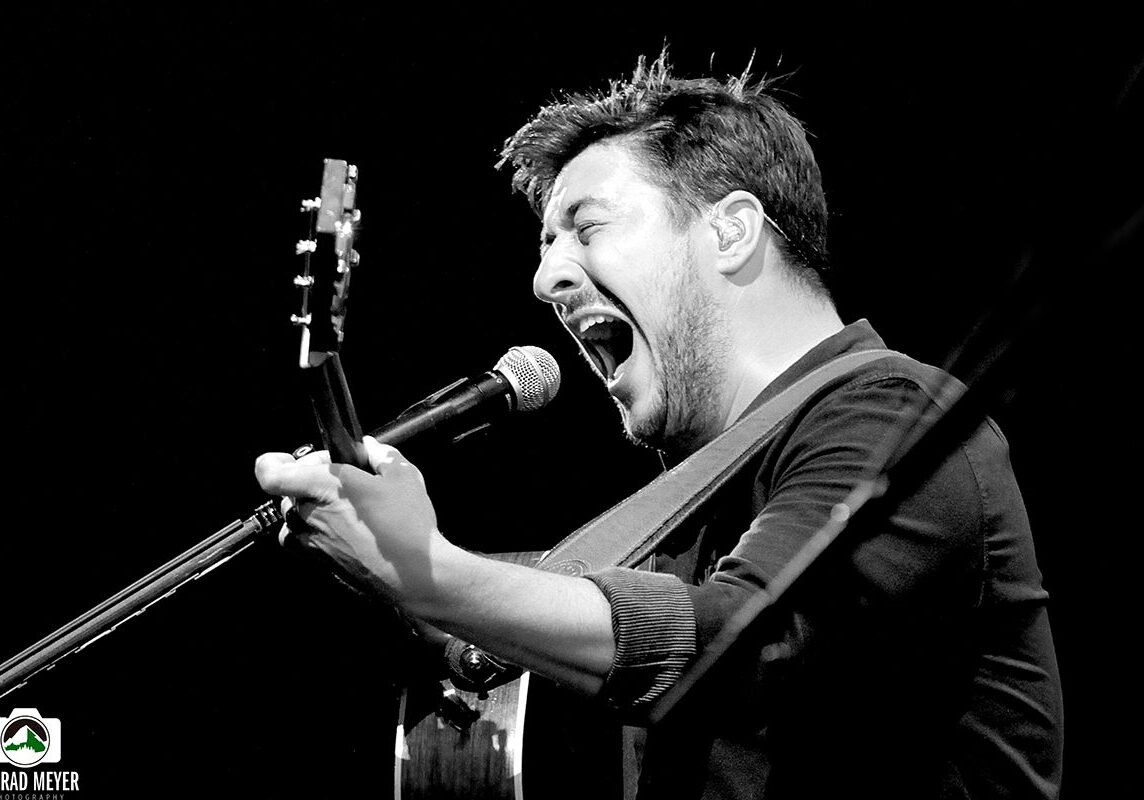 Singer passionately performing with a guitar.