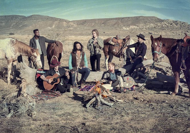 Group sitting by campfire with horses.