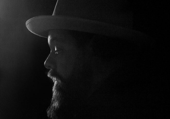 Silhouetted man in hat with beard.