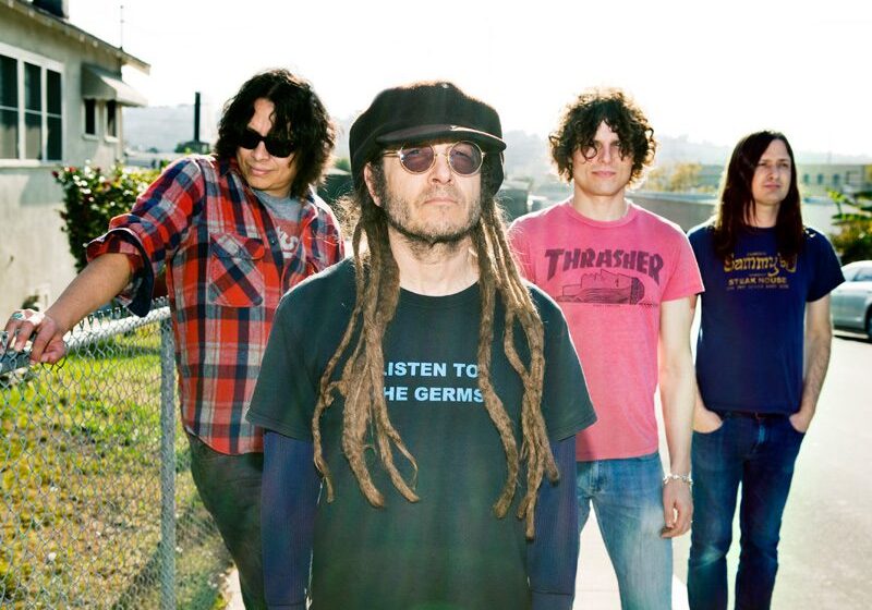 Band members posing outdoors in casual attire.