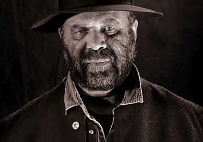Man in hat with intense expression.