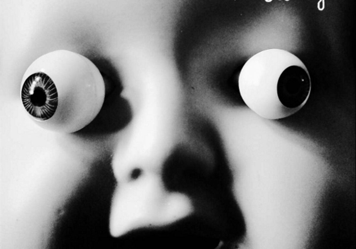 Surreal doll face with exaggerated eyes.