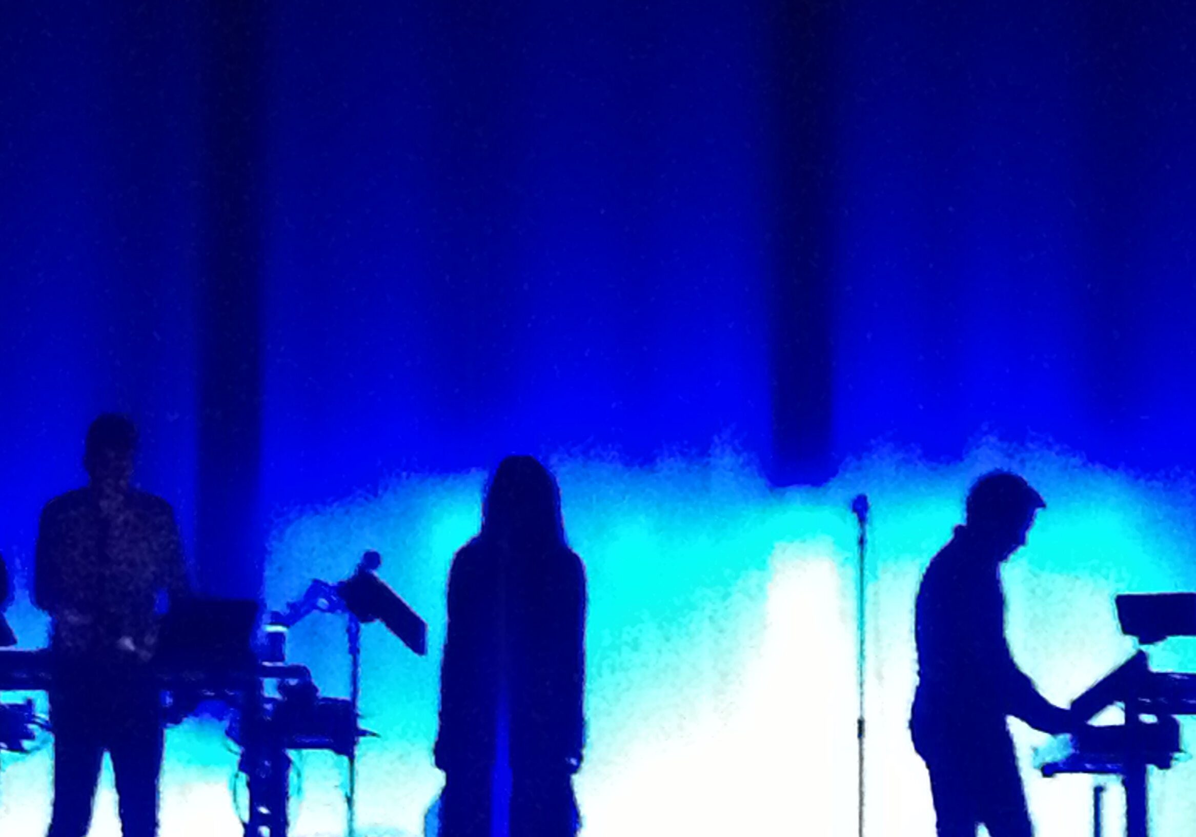 Silhouetted band performing on blue-lit stage.