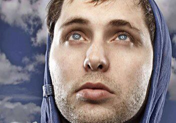 Man in hoodie looking up at sky.