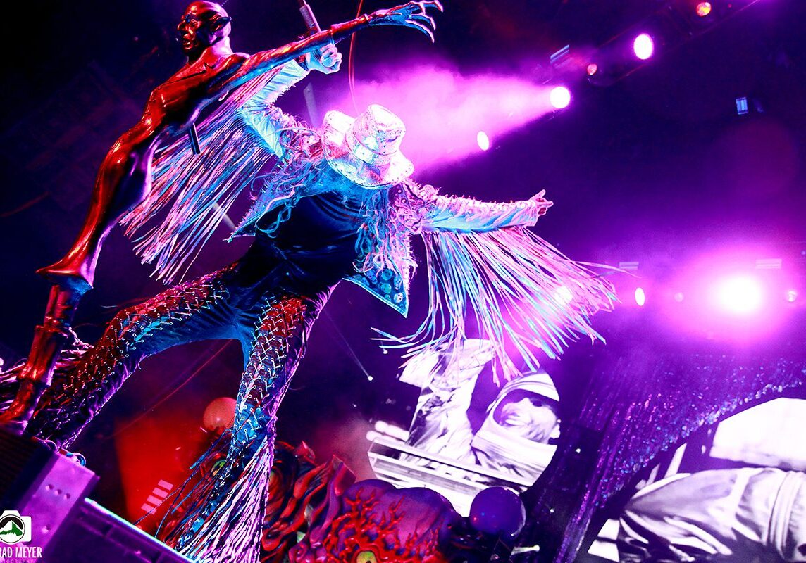 Performer in vibrant costume on stage, dancing.