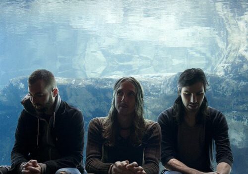Three people sitting in front of aquarium.