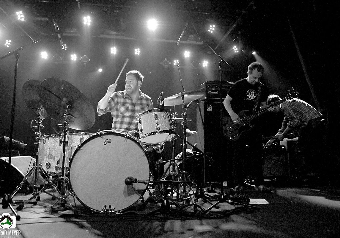 Band performing live on stage with instruments.